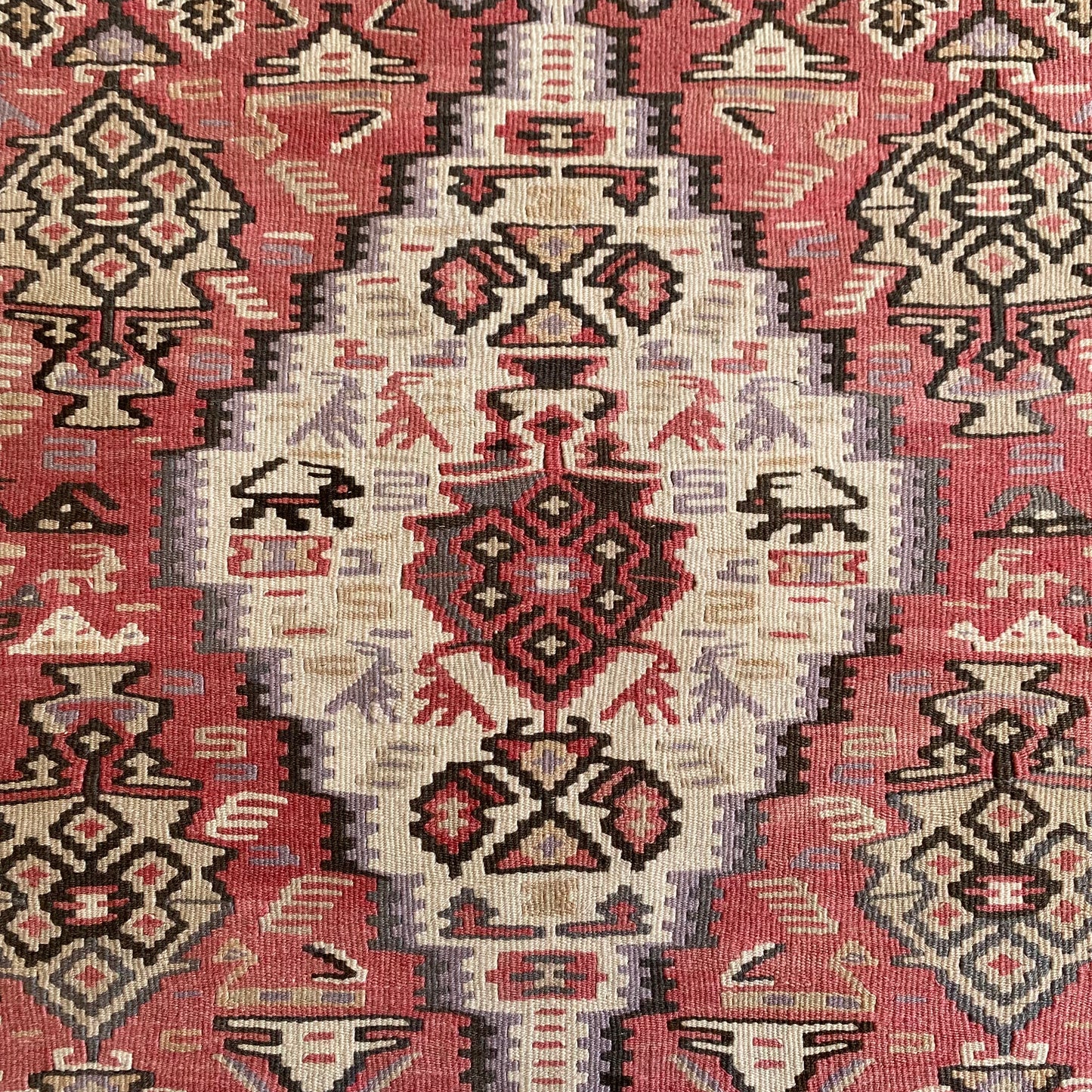 Close up detail of central medallion on Kurdish Senneh kilim rug with geometric and animal motifs